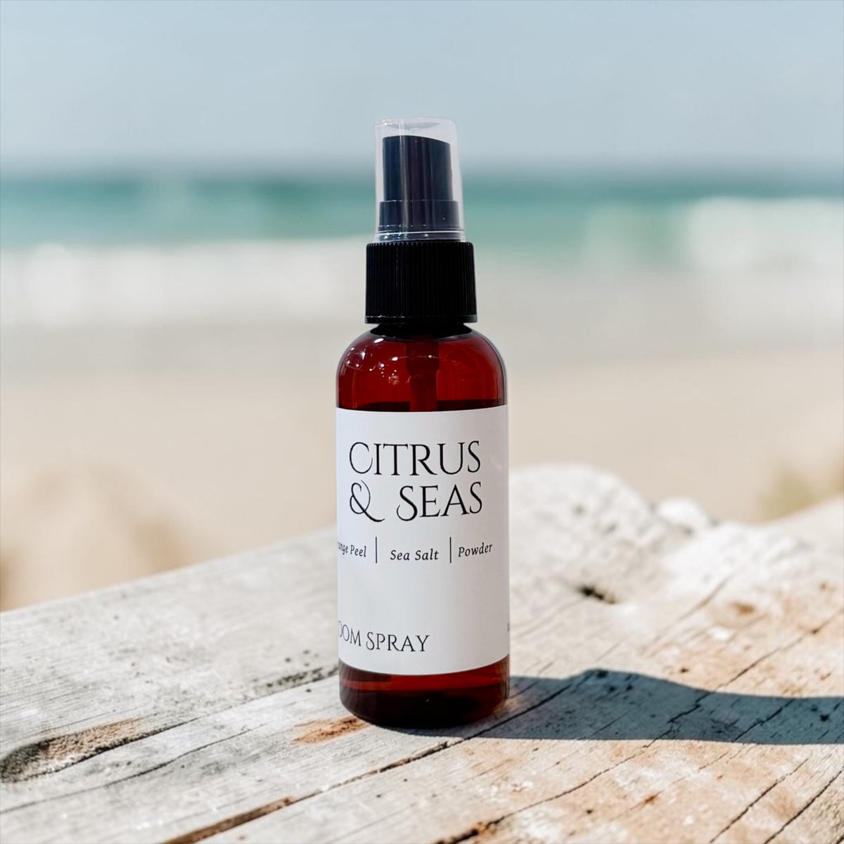 Citrus & Seas room spray bottle with pump top on a weathered wood table by the beach