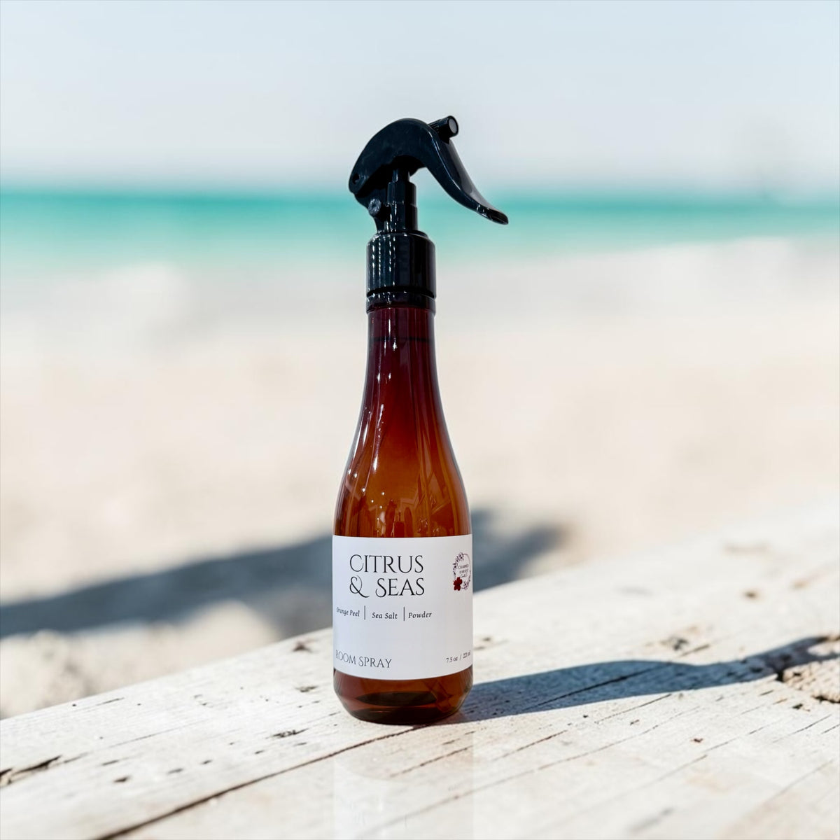 7.5 oz Citrus & Seas trigger spray bottle on a driftwood table with the beach in the background