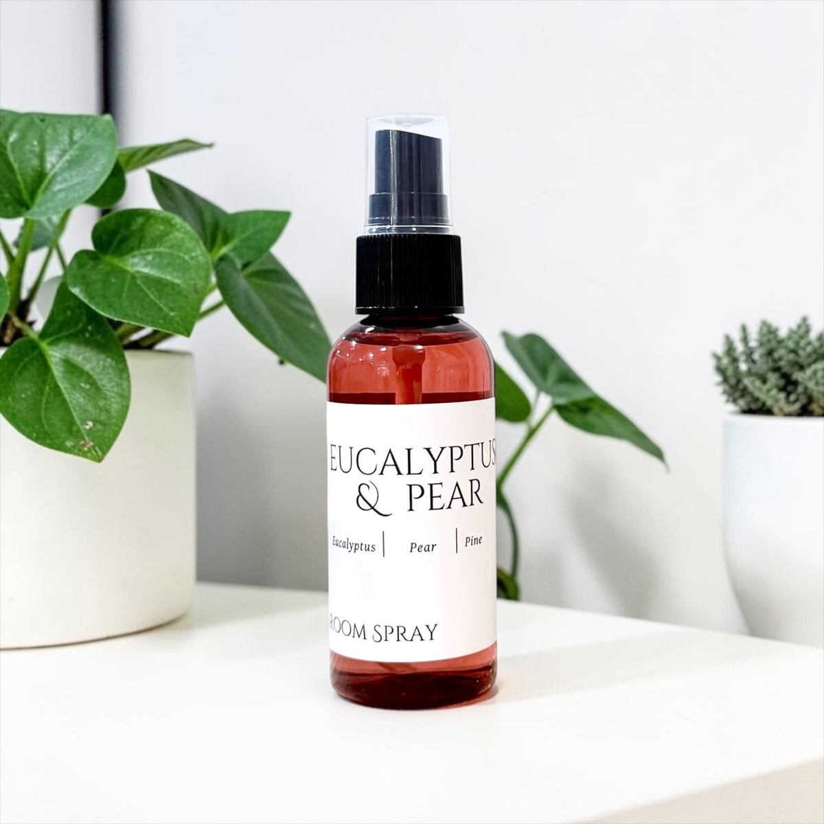 Eucalyptus & Pear room spray bottle with eucalyptus leaves on a white background
