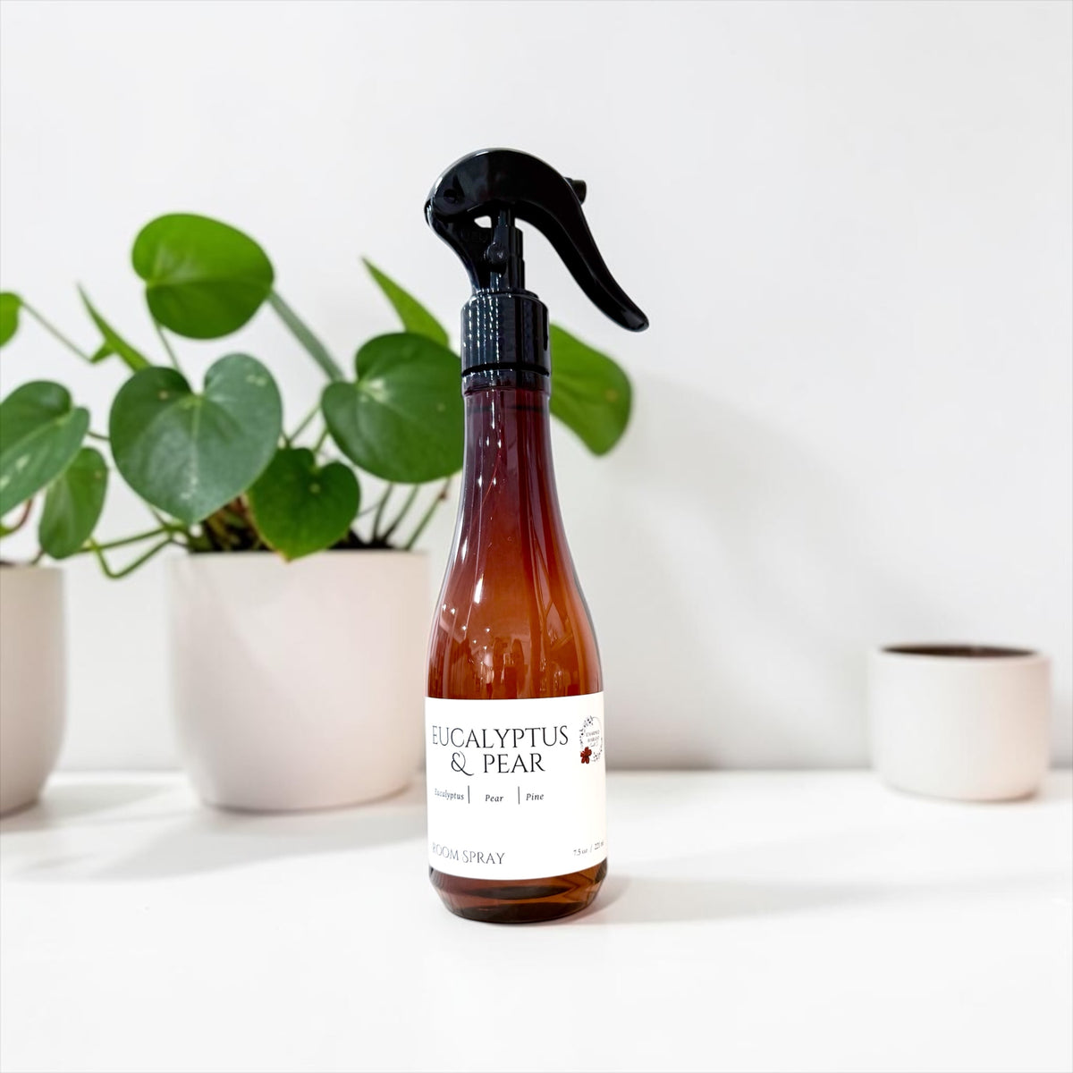 Eucalyptus & Pear room spray bottle beside a potted plant