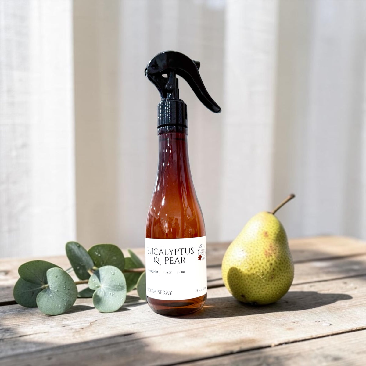 Eucalyptus & Pear room spray bottle with a pear and eucalyptus leaves on a wood table