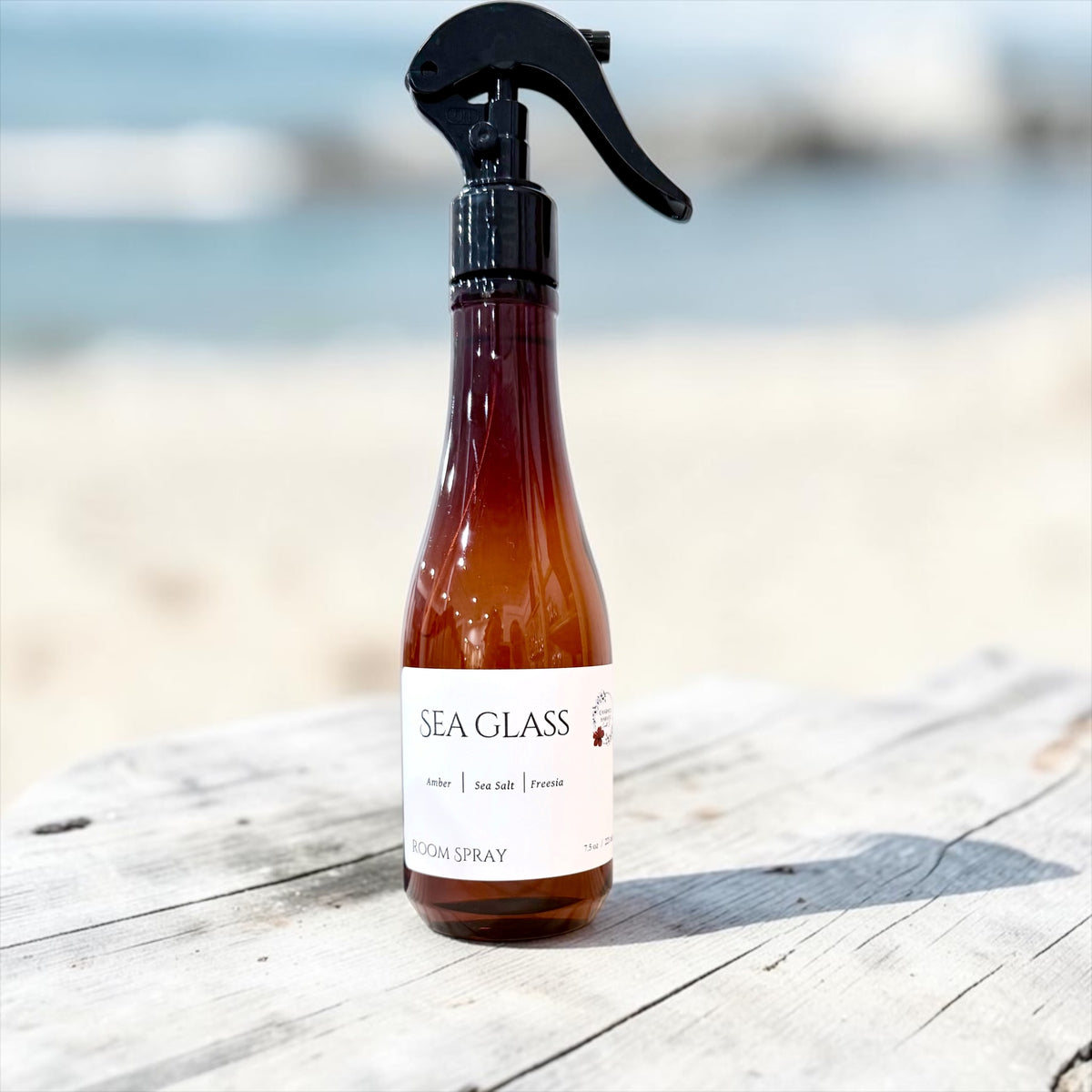 Sea Glass room spray bottle on a driftwood plank by the shore