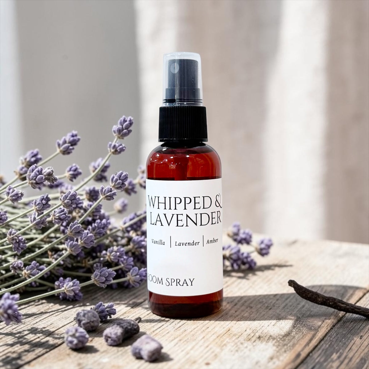 Whipped Lavender room spray bottle with fresh lavender sprigs on a wood table