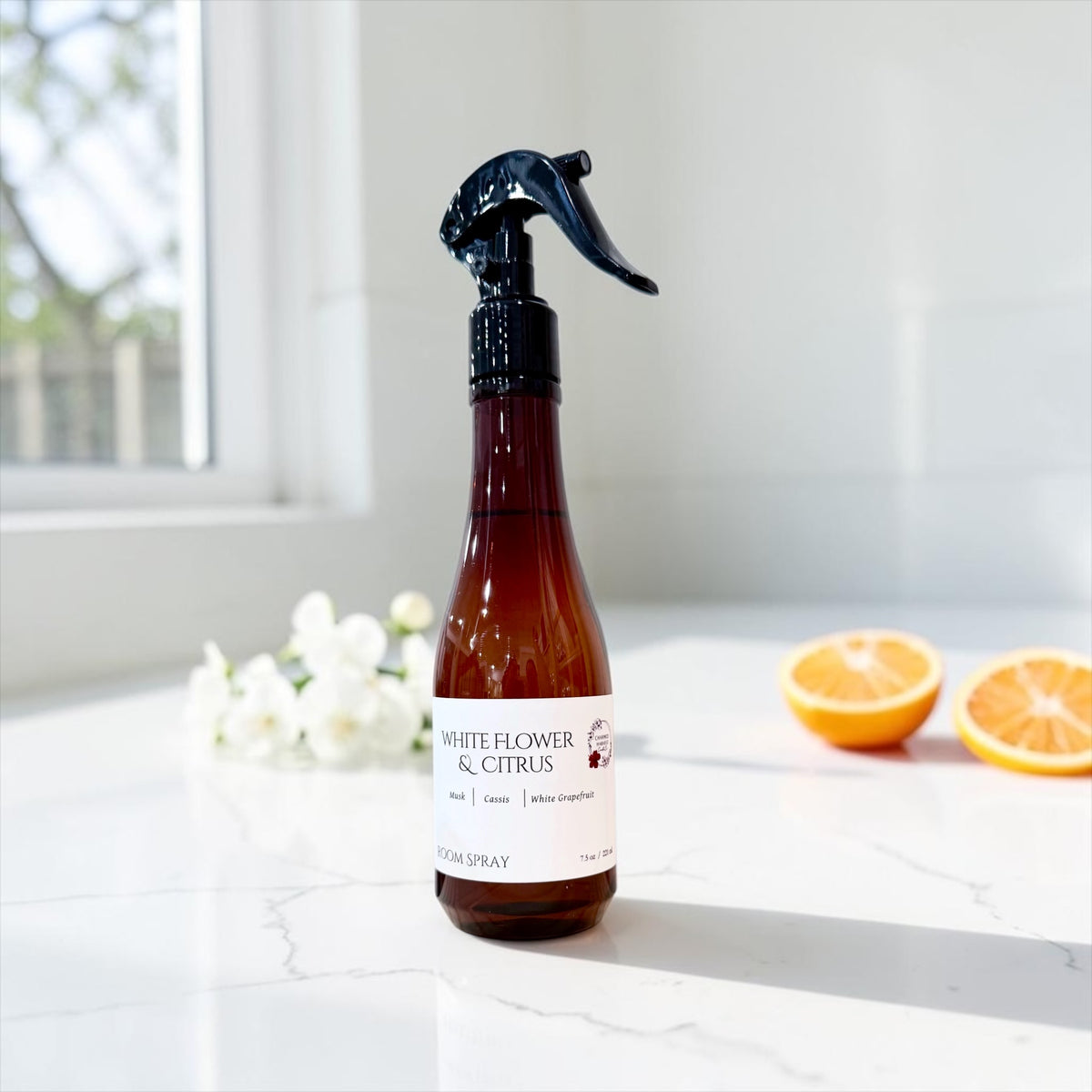White Flower and Citrus room spray bottle with fresh orange slices on a white surface